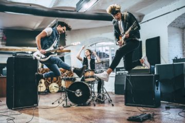 An excited rock band playing their instruments with enthusiasm.