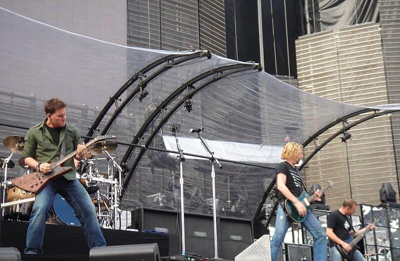 The band Nickleback playing instruments on stage.