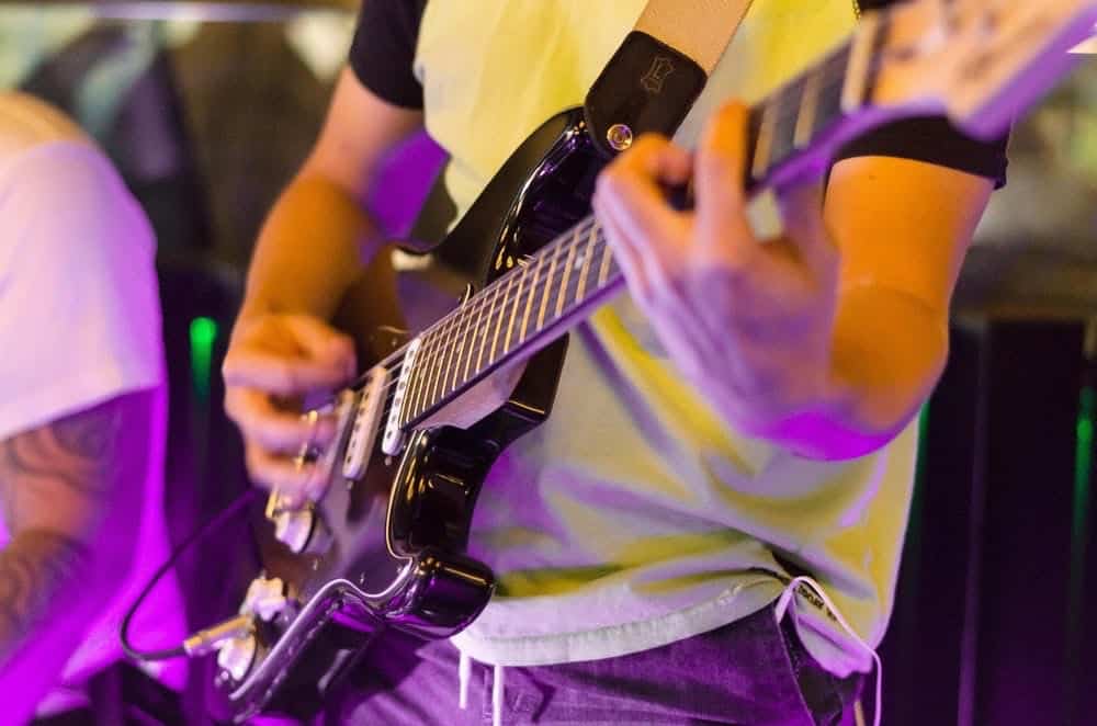 A musician playing a barre chord on the guitar.