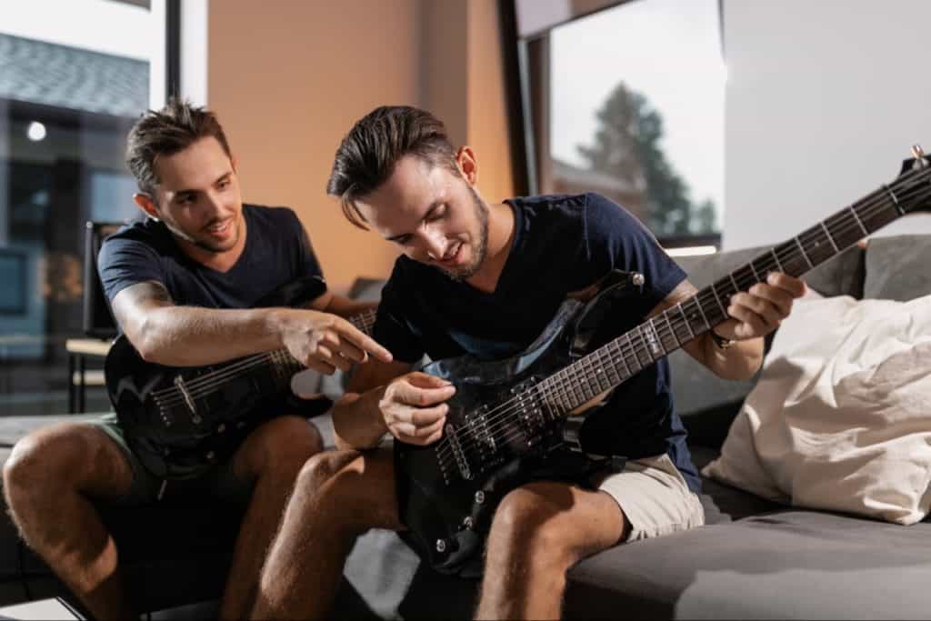 Musician pointing to another musician, on what to do on guitar.