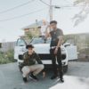 Three young men chilling outside of a white car. Photo by WoodysMedia