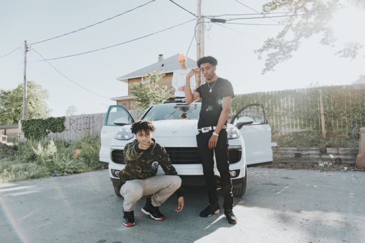 Three young men chilling outside of a white car. Photo by WoodysMedia